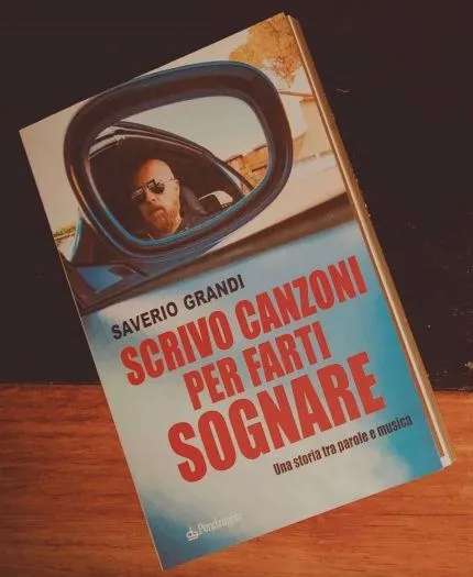 Il libro Scrivo canzoni per farti sognare appoggiato su un tavolo di legno